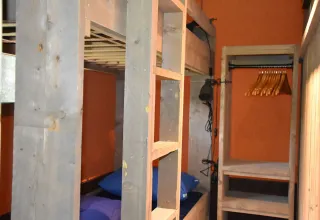 Binnenzicht in een safari tent lodge Veluwe op Camping Samoza, met stapelbed en open kleerkast.