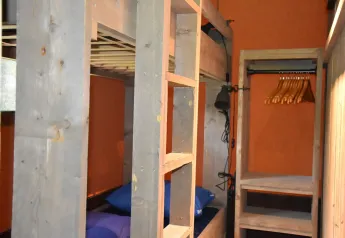 Interno di una tenda lodge safari al Camping Samoza con letti a castello e armadio aperto in legno.