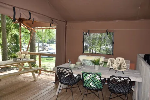 Safaritent bij Veluwe Lodge op Camping Samoza, Nederland, met houten terras, picknicktafel en stoelen.