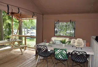 Safari tent at Veluwe Lodge, Camping Samoza, Netherlands, with wooden deck, picnic table, and chairs.