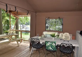 Safari tent at Veluwe Lodge, Camping Samoza, Netherlands, with wooden deck, picnic table, and chairs.