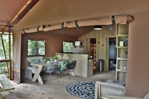 Interieur van de safari tent Veluwe Lodge op Camping Samoza, met gezellige eet- en zithoek in het groen.