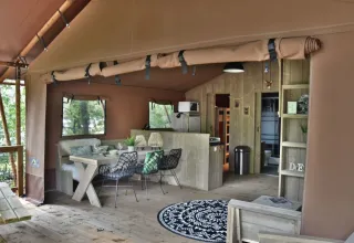 Vista interior de la tienda safari Veluwe Lodge en Camping Samoza, con comedor y sala de estar acogedores.