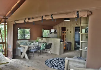 Vista interior de la tienda safari Veluwe Lodge en Camping Samoza, con comedor y sala de estar acogedores.