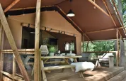 Safaritent Veluwe Lodge bij Camping Samoza in Nederland met houten terras, picknicktafel en banken.