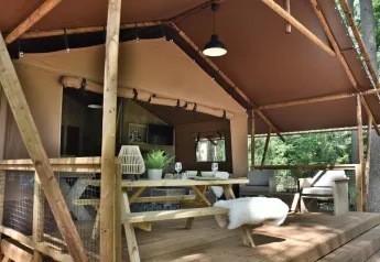 Tienda safari Veluwe Lodge en Camping Samoza, Países Bajos, con terraza de madera y muebles de exterior.
