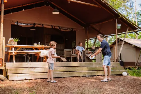 Familie die plezier maakt aan een safaritent bij Veluwe Lodge op Camping Samoza in Nederland, omringd door natuur.