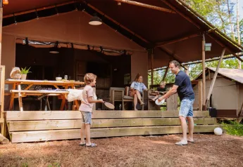 Familia disfrutando fuera de una tienda safari en Veluwe Lodge del Camping Samoza, Países Bajos, en la naturaleza.