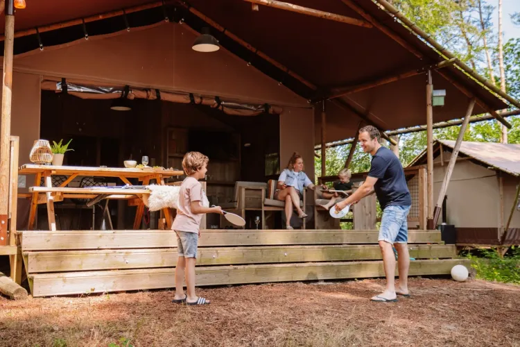 Familia disfrutando fuera de una tienda safari en Veluwe Lodge del Camping Samoza, Países Bajos, en la naturaleza.
