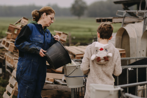 Eine Frau und ein Kind helfen auf dem Bauernhof im Feather Down De Oude Melkstal in Nord-Brabant, Niederlande.