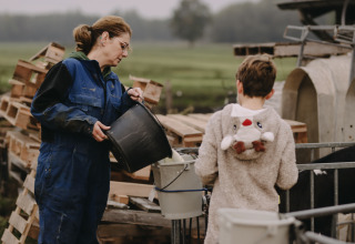 Een vrouw en een kind helpen samen op de boerderij bij Feather Down De Oude Melkstal in Noord-Brabant, Nederland.