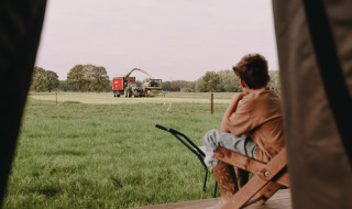 Garçon assis sur la terrasse regarde des machines agricoles dans un champ près de Valkenswaard, Brabant-Septentrional.