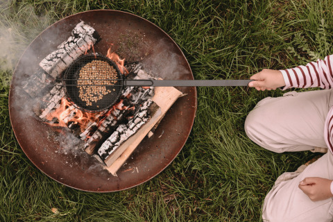 Person roasting popcorn over an open fire at Feather Down De Oude Melkstal holiday park, North-Brabant, Netherlands.