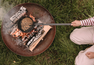 Person roasting popcorn over an open fire at Feather Down De Oude Melkstal holiday park, North-Brabant, Netherlands.