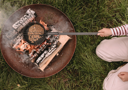 Persoon roostert popcorn boven open vuur bij Feather Down De Oude Melkstal vakantielocatie in Noord-Brabant, Nederland.