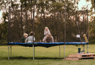 Kinderen en volwassene spelen op een trampoline bij Feather Down De Oude Melkstal in Noord-Brabant.