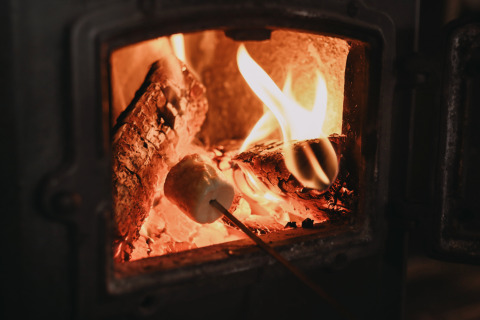 Roasting marshmallows over a wood stove at Feather Down De Oude Melkstal, holiday park in North Brabant, Netherlands.