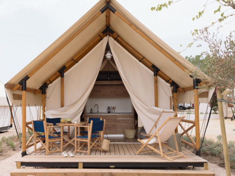 Safari tent Glamping Family Plus met houten terras, zitplaatsen, tafel en zichtbare keuken in natuurgebied.