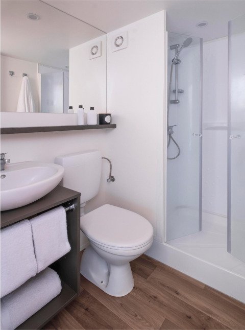 Moderne badkamer in een Glamping Family Plus safaritent bij Wecamp Cadaqués, met douche en handdoeken.
