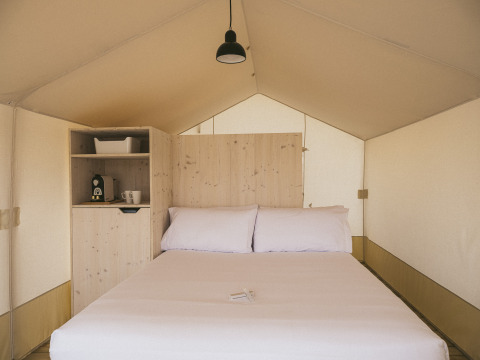 Interior de una tienda Cottage Family Tent en Wecamp Cadaqués, España, con cama doble y cafetera.