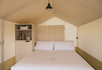 Interior de una tienda Cottage Family Tent en Wecamp Cadaqués, España, con cama doble y cafetera.