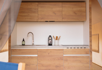 Vista interna di una cucina glamping accogliente con armadietti in legno in una tenda safari a Wecamp Cadaqués, Spagna.