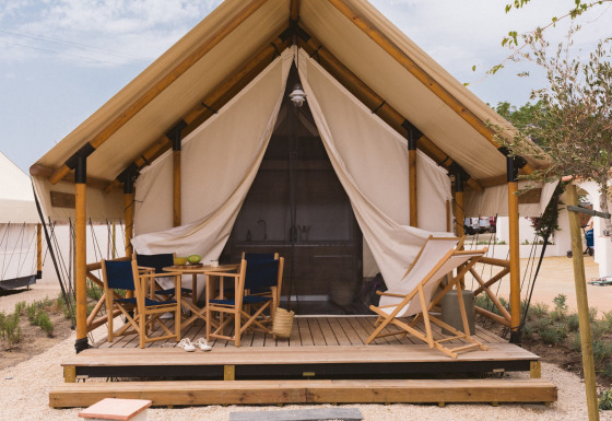 Safari tent Glamping Comfort met eigen sanitaire voorzieningen, houten veranda en comfortabele stoelen.