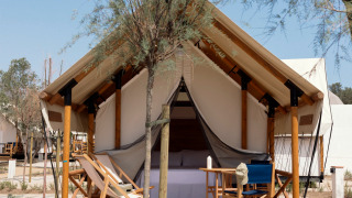 Luksuriøs safari telt Glamping Couple med sanitære faciliteter, træterrasse og afslappende stole.