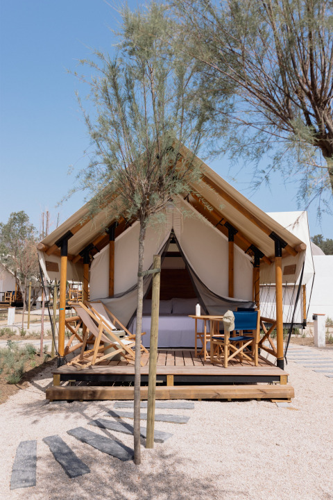 Safari tent Glamping Couple met sanitair, houten terras, ligstoelen en bomen in een rustige omgeving.