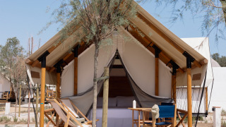 Safari tent Glamping Couple met sanitair, houten terras, ligstoelen en bomen in een rustige omgeving.