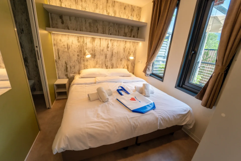 Modern lodge-slaapkamer met tweepersoonsbed, grote ramen en rustieke inrichting bij Vacanze Glamping Boutique, Italië.