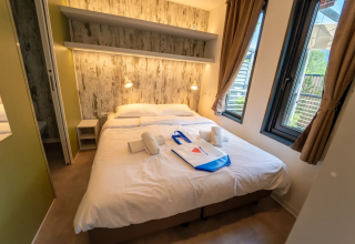 Modern lodge-slaapkamer met tweepersoonsbed, grote ramen en rustieke inrichting bij Vacanze Glamping Boutique, Italië.