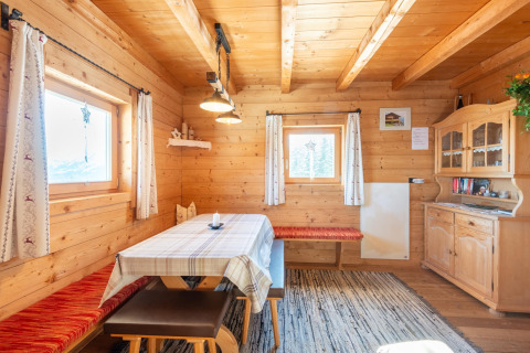 Hyggelig træhytte med spisebord, bænk og vitrineskab på Almhütte Nase i Østrig, naturligt lysindfald.