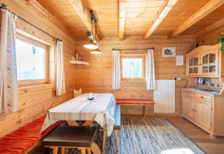 Hyggelig træhytte med spisebord, bænk og vitrineskab på Almhütte Nase i Østrig, naturligt lysindfald.
