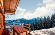 Vista desde el chalet Almhütte Nase en Austria, con banco de madera y montañas nevadas.