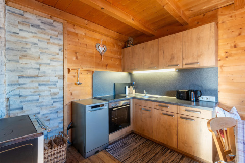 Moderne alpehytte køkken med trævægge, grå apparater og hyggelig belysning på 'Almhütte Nase' i Østrig.