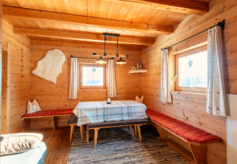Cálido comedor de madera en el chalet Almhütte Nase en Austria, con bancos y vistas a las montañas.