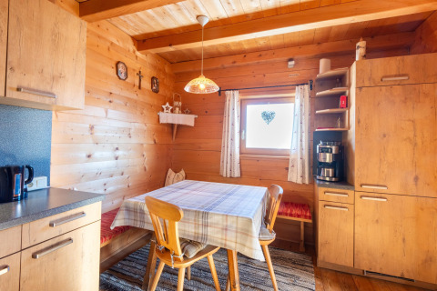 Hyggeligt køkkenhjørne i træ ved Almhütte Nase, Østrig, med spisebord, bænk og moderne apparater.