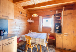 Hyggeligt køkkenhjørne i træ ved Almhütte Nase, Østrig, med spisebord, bænk og moderne apparater.