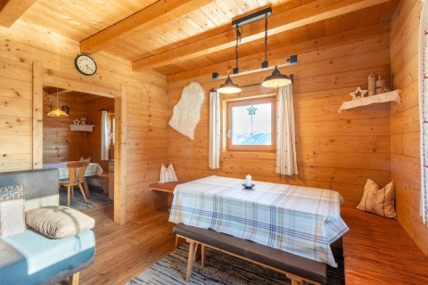 Træinteriør af chalet Almhütte Nase i Østrig med spisebord, bænk og hyggelig belysning.