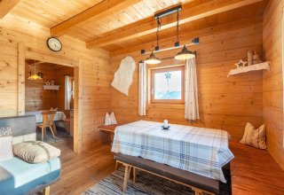 Træinteriør af chalet Almhütte Nase i Østrig med spisebord, bænk og hyggelig belysning.