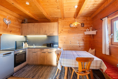 Træbeklædt køkken og spiseområde i Almhütte Nase, Østrig, med naturligt lys og hyggelig atmosfære.
