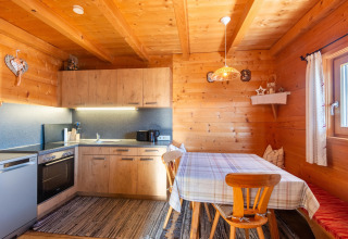 Træbeklædt køkken og spiseområde i Almhütte Nase, Østrig, med naturligt lys og hyggelig atmosfære.