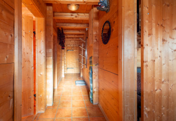 Pasillo revestido de madera con suelo de baldosas en el chalet Almhütte Nase, Austria, con luz natural cálida.
