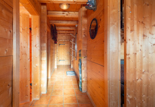 Træbeklædt gang med klinkegulv i chalet Almhütte Nase i Østrig, oplyst af naturligt lys og varmt interiør.