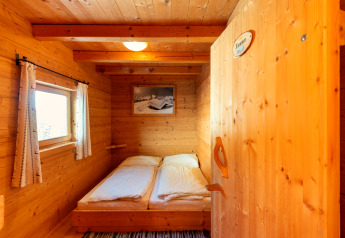 Habitación de madera luminosa en Almhütte Nase, Austria, con cama doble y ventana con vistas.