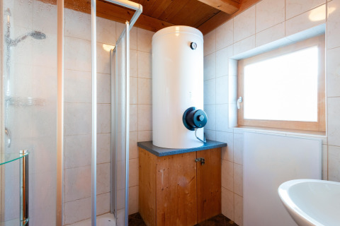Moderne badeværelse med varmtvandsbeholder, brusekabine og vindue på Almhütte Nase i Østrig.