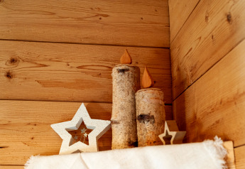 Estrellas de madera y velas de tronco en estante de chalet Almhütte Nase, Austria, con paredes de madera.