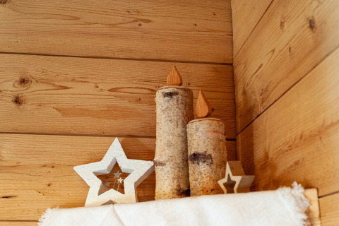 Dekorative træstjerner og trælys på træhylde i chalet Almhütte Nase, Østrig, med hyggelig bjælkevæg.