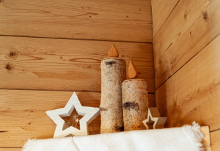 Dekorative træstjerner og trælys på træhylde i chalet Almhütte Nase, Østrig, med hyggelig bjælkevæg.